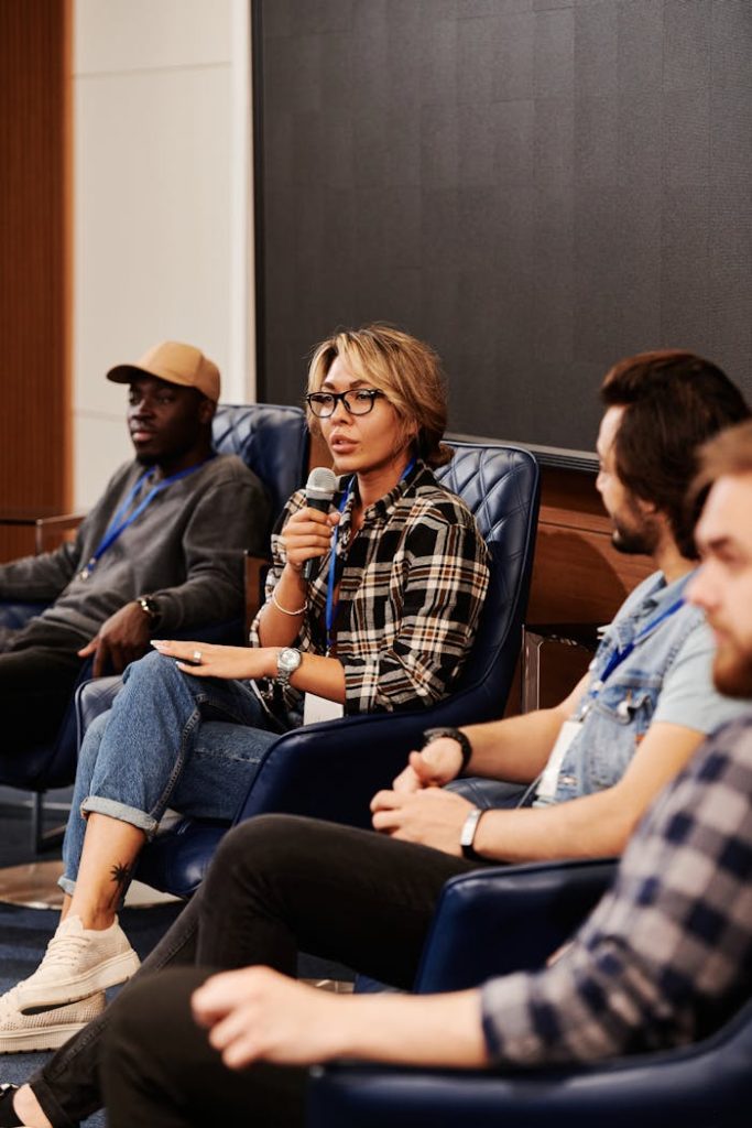 A diverse group of adults engaged in a panel discussion during a business seminar. Indoors setting.