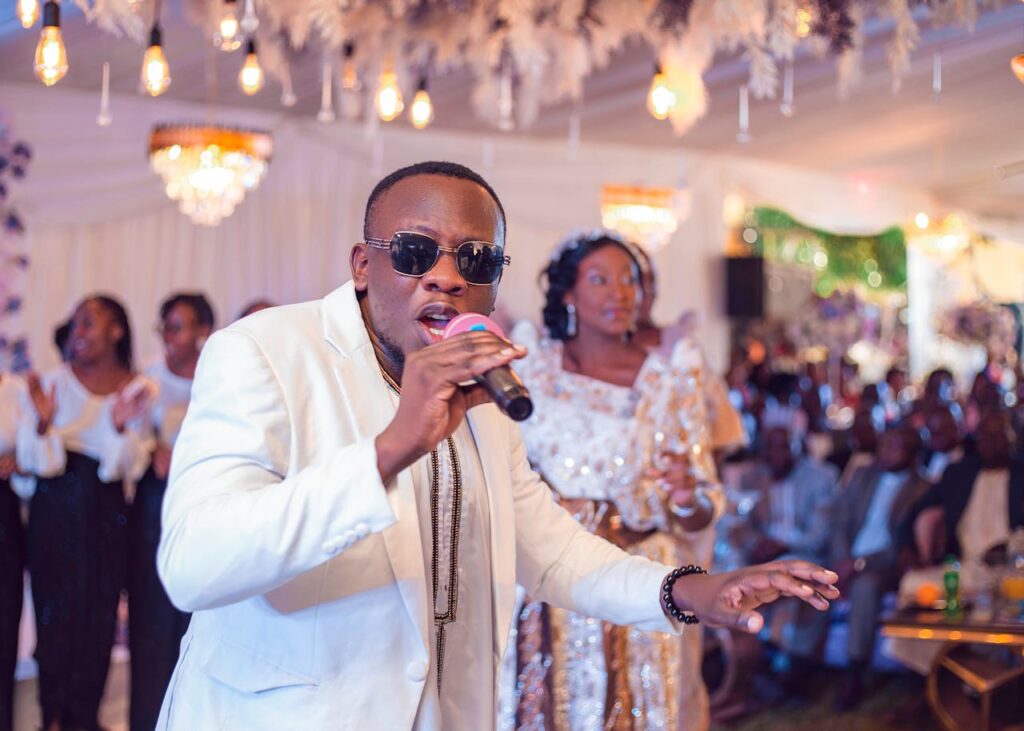 Singer in sunglasses performing at lively wedding celebration indoors.