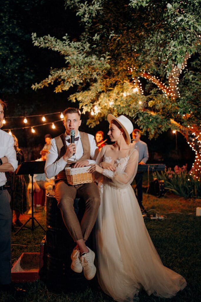 Elegant outdoor wedding reception with bride and groom speaking under twinkling lights.